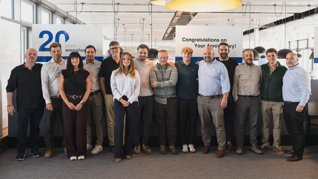 İspanya'dan gelen wenglor ekibi kantinin lounge alanında, şubenin kuruluş yıldönümünü kutlayan pankartların önünde duruyor.