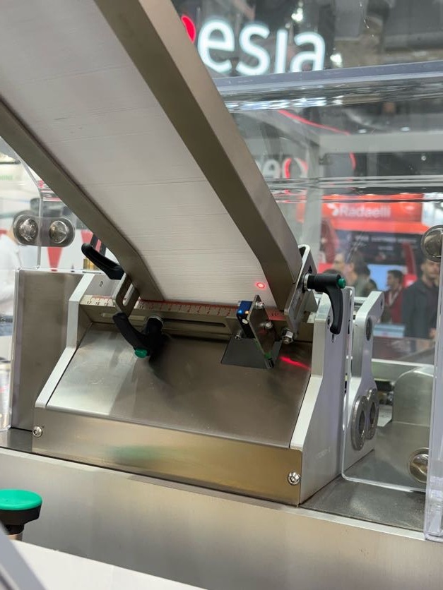 เซ็นเซอร์สะท้อนแสงที่มีจุดแสงสีแดงตรวจจับผลิตภัณฑ์ที่ทางออกของสายพานลำเลียงแบบเอียง